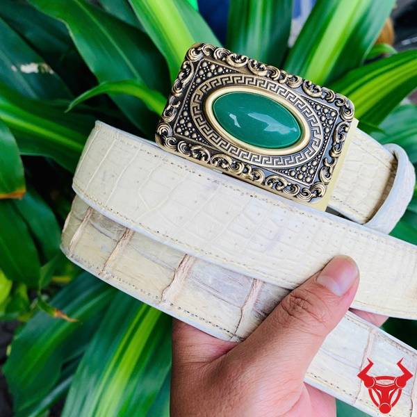 Hình ảnh thắt lưng da cá sấu bạch tạng TSK95, mặt khóa đồng nguyên chất, cầm tay với nền lá xanh.
