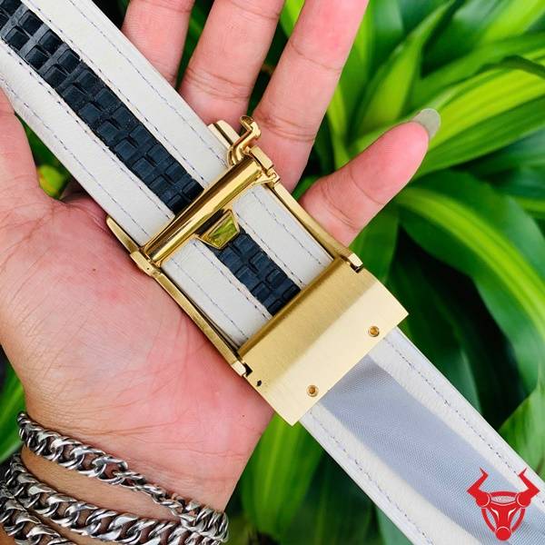 Hình ảnh thắt lưng da cá sấu bạch tạng TSK95, mặt khóa đồng nguyên chất, cầm tay trên nền lá xanh.