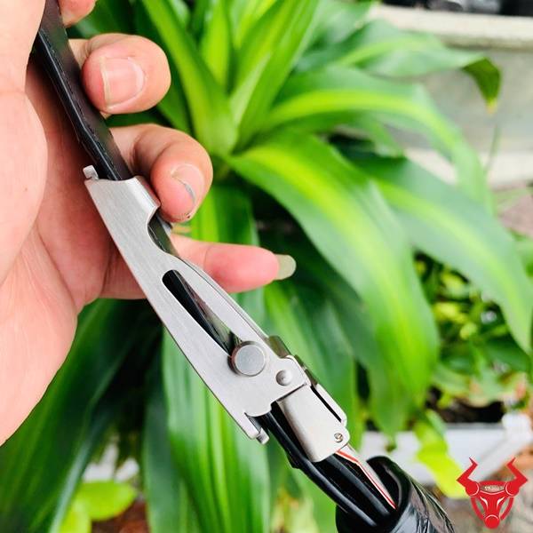 Hình ảnh thắt lưng da cá sấu TSK32, khóa lăn inox họa tiết cá sấu, cầm tay trên nền lá xanh.
