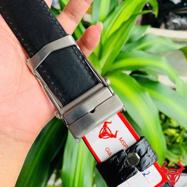 Hình ảnh thắt lưng da cá sấu TSK32, khóa lăn inox họa tiết cá sấu, cầm tay giữa lá xanh.