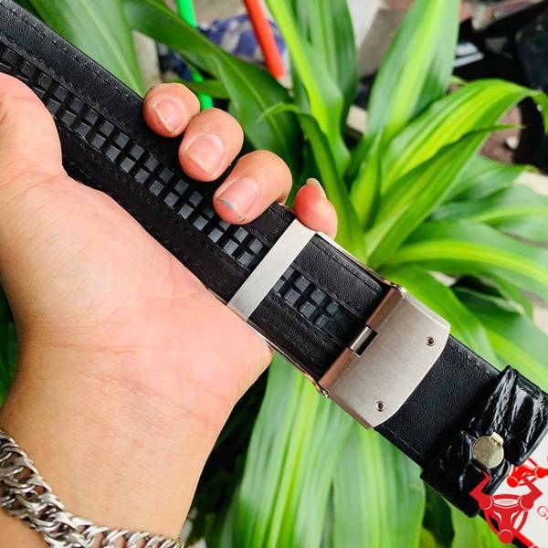 Hình ảnh thắt lưng da cá sấu TSK73, ray trượt tinh xảo, mặt khóa inox mạ bạc, cầm tay trên nền lá xanh.