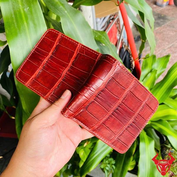 Hình ví da cá sấu nâu đỏ VBAA8, thiết kế độc đáo, nền cây xanh.