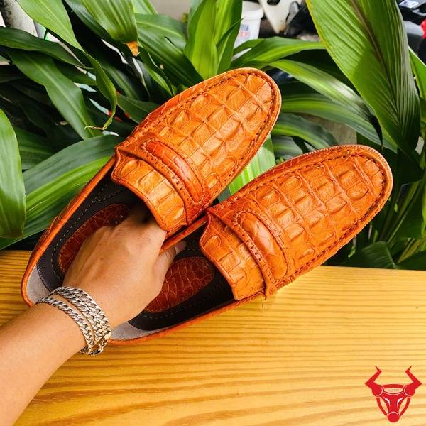 Hình giày tây GCA1 da gai lưng cá sấu màu vàng cam cầm tay, nền lá, cao cấp đẳng cấp quý ông.