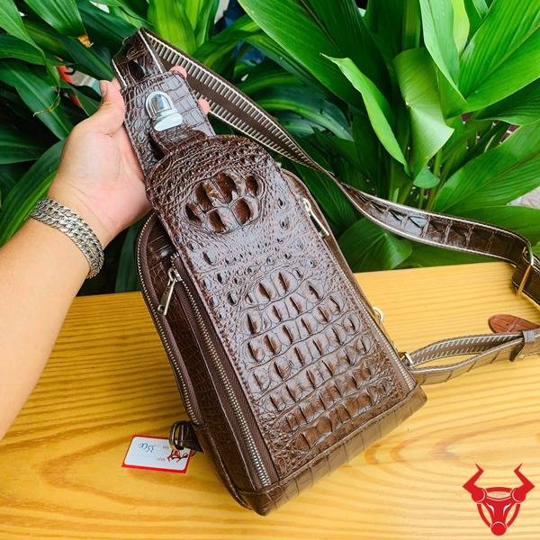 Ảnh túi đeo chéo TTL05 da cá sấu màu nâu đất, nền lá, thể hiện cao cấp phong cách đẳng cấp.