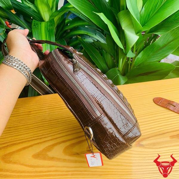 Hình túi TTL05 da cá sấu màu nâu đất trên bàn gỗ, nền lá, cao cấp phong cách đẳng cấp.