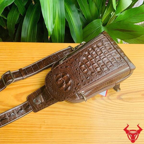 Ảnh túi TTL05 da cá sấu màu nâu đất trên bàn, nền lá, cao cấp phong cách đẳng cấp.