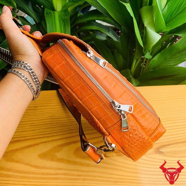 Hình túi đeo chéo TTL05 da cá sấu gù màu vàng cam, nền lá, cao cấp phong cách.
