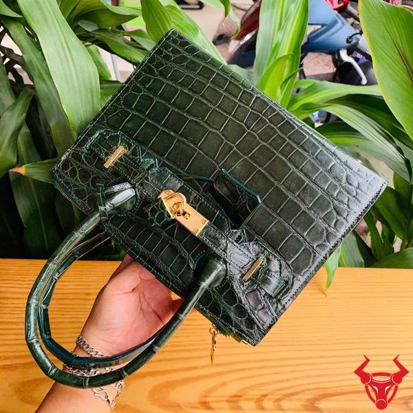 Ảnh túi xách TTL01 da cá sấu bóng kính, nền lá xanh, cao cấp sang chảnh quý phái.