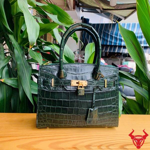 Hình túi xách TTL01 da cá sấu bóng kính, nền lá xanh, cao cấp sang chảnh quý phái.