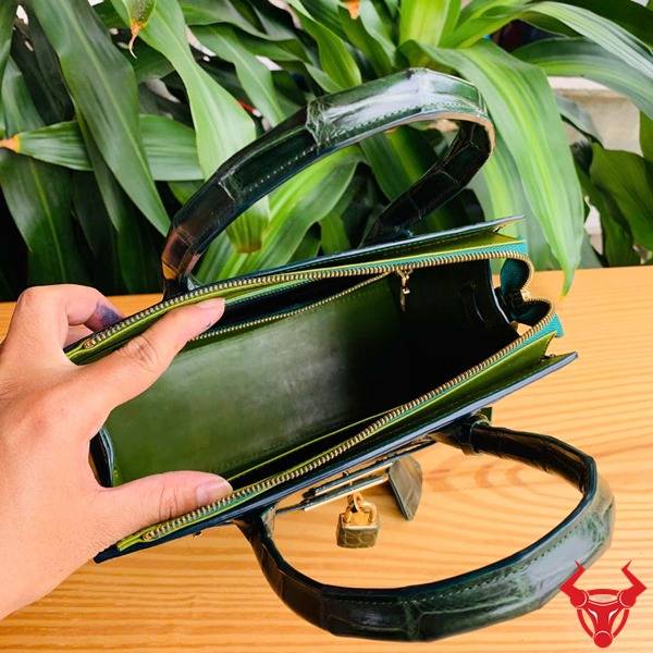 Ảnh túi xách TTL01 da cá sấu bóng kính trên bàn gỗ, nền lá, cao cấp sang chảnh quý phái.
