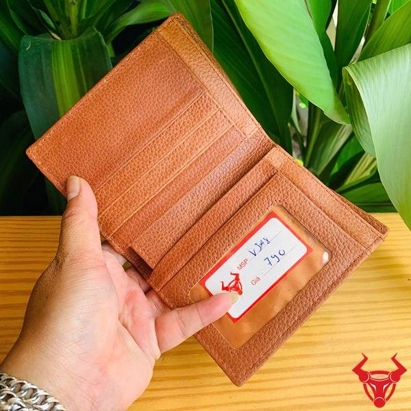 Ảnh cầm ví form đứng VJA8 da cá sấu màu nâu đỏ sáng, nền lá, cao cấp sang trọng.
