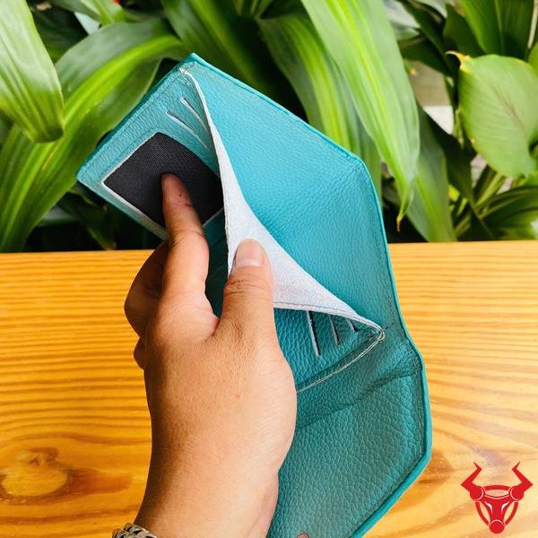 Ba chiếc ví nhỏ da cá sấu xanh ngọc trong ảnh, cầm tay với nền lá cây, thể hiện phong cách thời trang hiện đại.