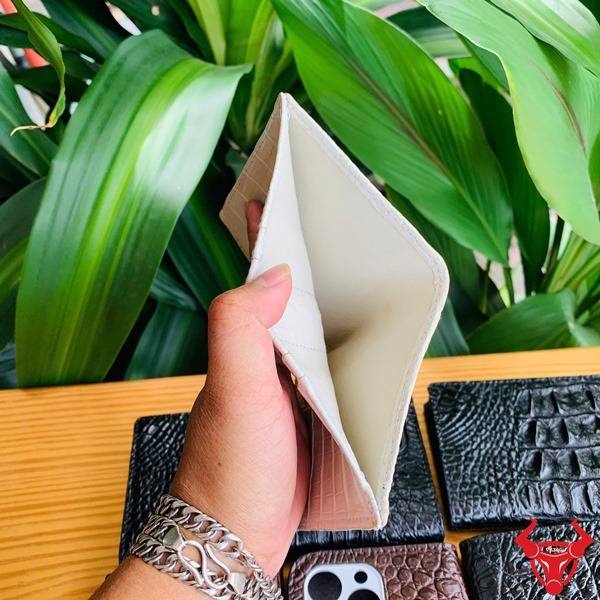 Ảnh chi tiết ví da cá sấu trắng mộc form đứng, cầm tay với vòng tay bạc.