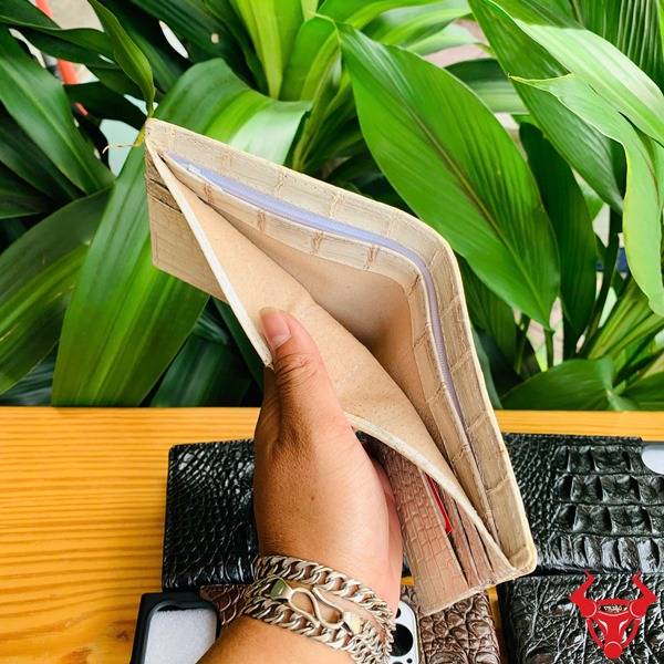 Bền Bỉ Thời Trang Cao Cấp Sang Trọng Ví Da Cá Sấu Bạch Tạng Nam Hình cầm ví da cá sấu bạch tạng vân nổi, nền lá xanh tươi và các sản phẩm da cá sấu khác.