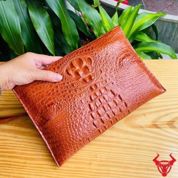 Clutch cầm tay da gù cá sấu CBCA4 màu nâu đỏ với vân da tự nhiên nổi bật.